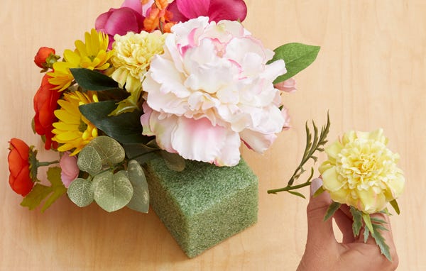 Hand putting flowers into green floral foam
