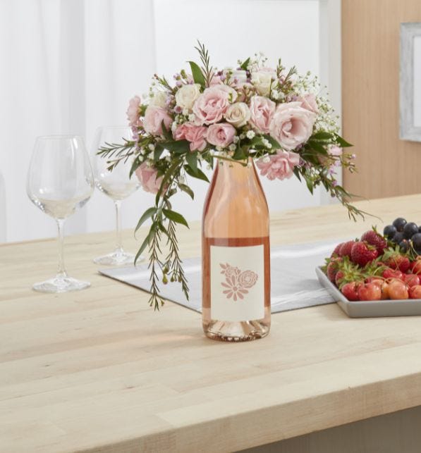 A fresh floral bouquet sits on top of a wine bottle depicting a current Mother's Day trend