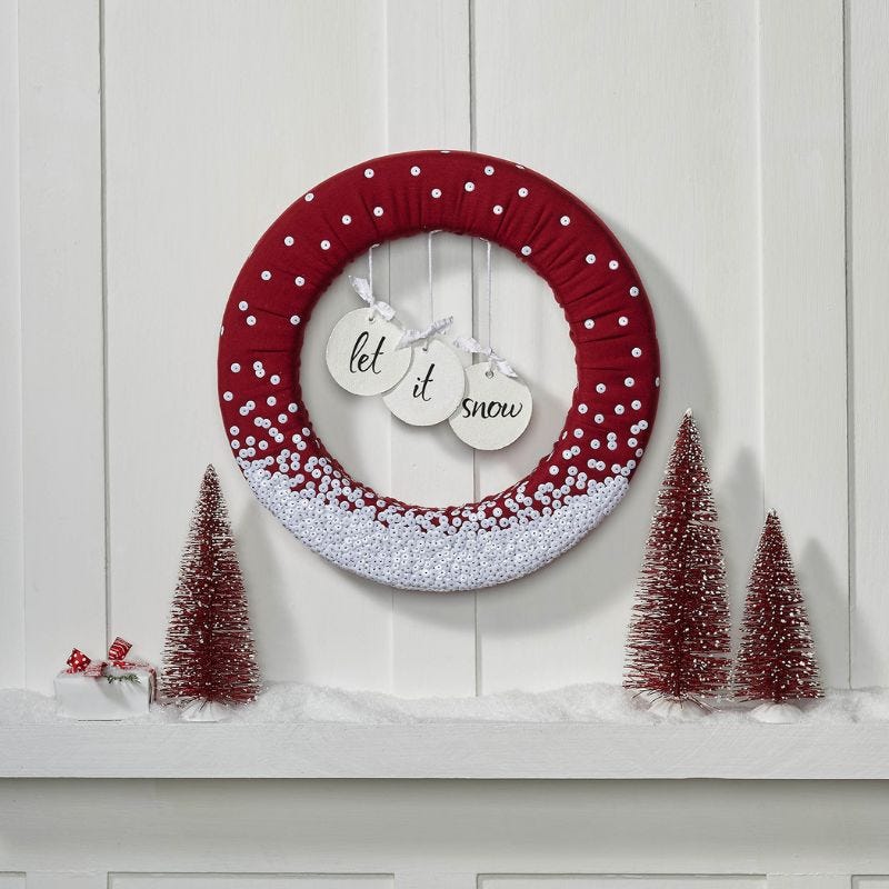 Foam wreath that reads Let It Snow and is wrapped in red fabric and adorned with white buttons to simulate snow