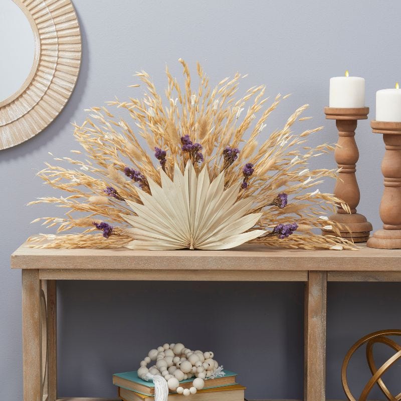 Natural florals are arranged in an half circle and displayed on a table with candles