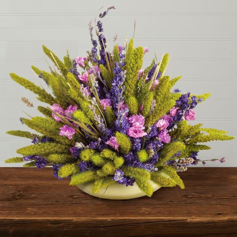 Pink, purple, and green dried floral memorial display on a table 