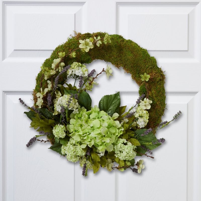 Green eco-friendly memorial wreath feature flower, moss, and greenery hanging on a white door